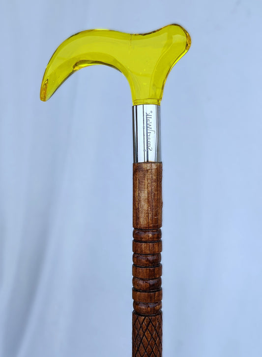 Wooden walking cane with a yellow glass handle on a light blue background